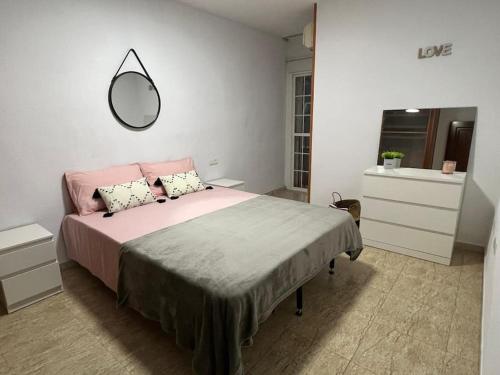 a bedroom with a pink bed and a mirror at Precioso piso con piscina a 10 min de la playa andando in Roquetas de Mar
