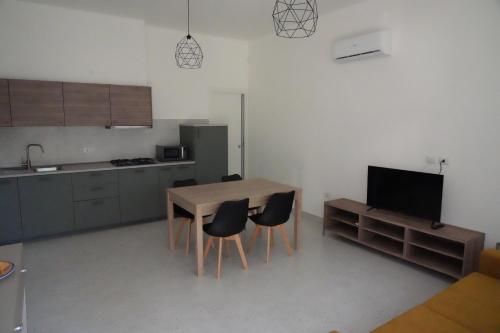 eine Küche mit einem Tisch und Stühlen sowie einem TV in der Unterkunft Appartamento AL FARO in Alba Adriatica