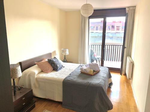 a bedroom with a bed and a window with a balcony at Apto La Manzanina con Parking in Villaviciosa