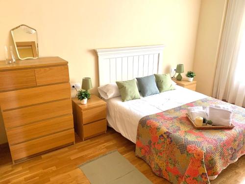 a bedroom with a bed with a dresser and a mirror at Apto La Manzanina con Parking in Villaviciosa