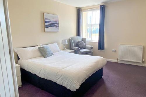 a bedroom with a large bed and a chair at Bramall House Accommodation in Fewston