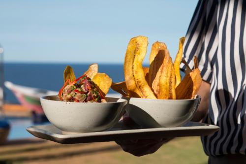 a person holding two bowls of food with french fries at Cala Margarita Hotel in Paraguachi