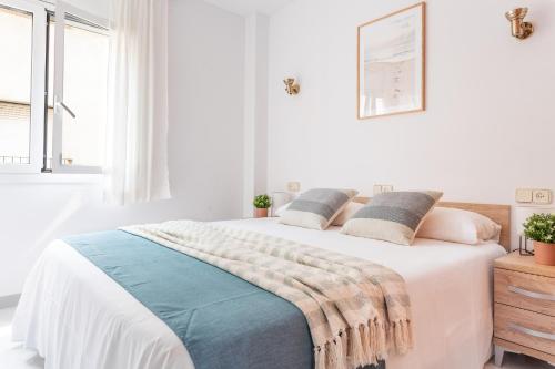 a white bedroom with a bed with a blanket on it at Apartamento El Capitan in L'Escala