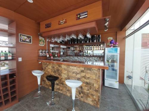 a bar with a counter with stools and a refrigerator at CASA CAMPESTRE SANTERRA in Tacna