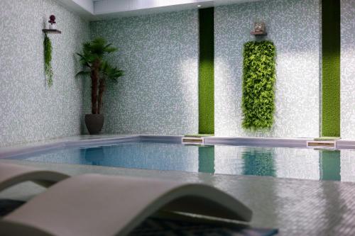 a room with a swimming pool with green plants on the wall at Hôtel et SPA du Château in Lagord