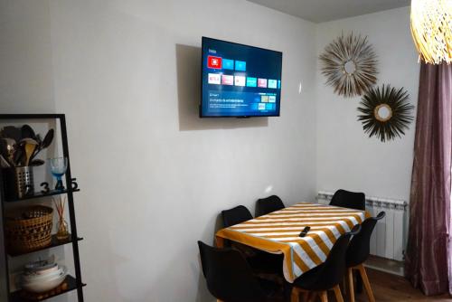 a dining room table with chairs and a tv on the wall at Casa Galdós in Logroño