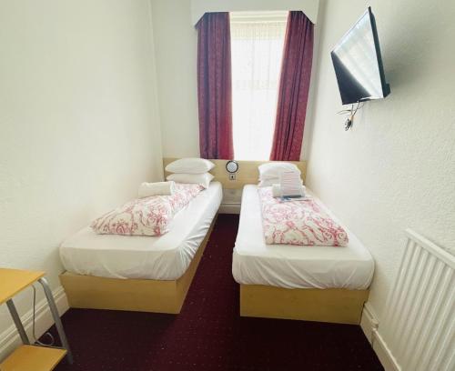two beds in a small room with a window at The Danescourt in Blackpool