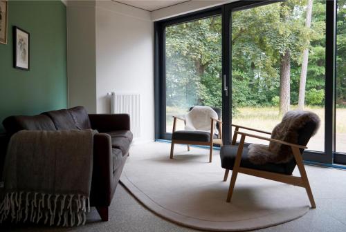 a living room with a couch and chairs and a window at Elf am See - Haus 7 in Templin