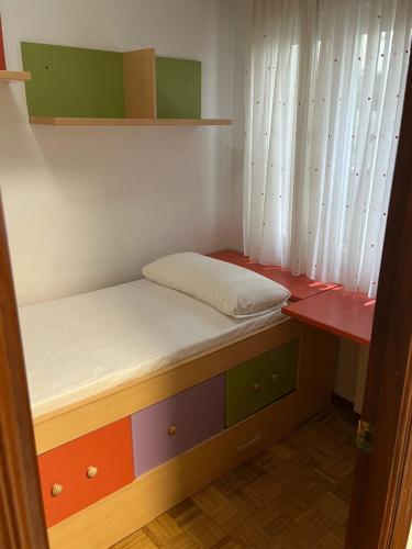 een kleine kamer met een bed en een raam bij Coqueto apto en Maliaño in Camargo