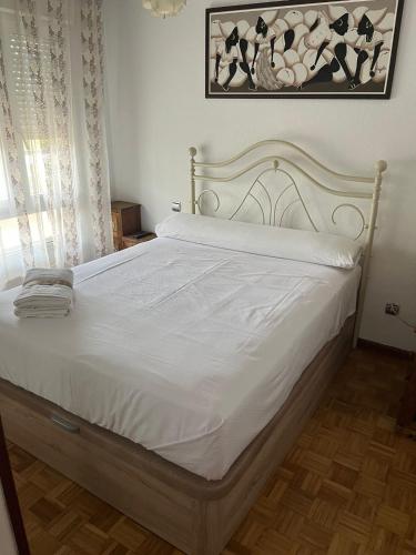 una camera da letto con un letto bianco con lenzuola bianche di Coqueto apto en Maliaño a Camargo