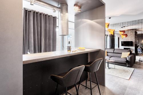 a kitchen with a bar with two chairs and a couch at Domaniewska Qbik Lofts in Warsaw