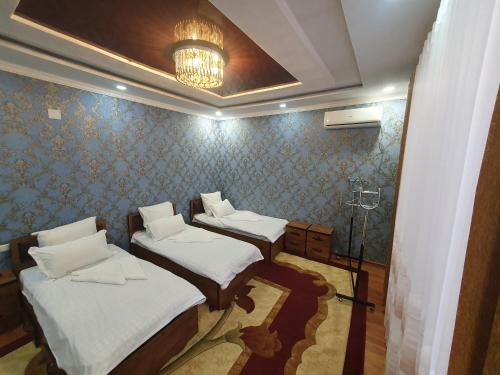 a room with three beds and a chandelier at Guest house Homely in Dushanbe