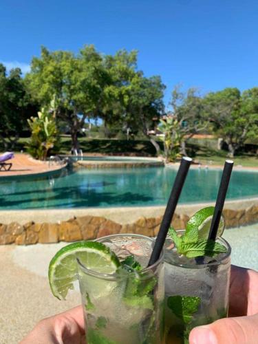 a person holding two drinks in front of a pool at Albufeira - Casa Balaia Resort in Albufeira