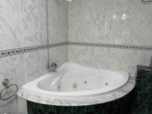 a white bath tub in a white tiled bathroom at Gran terraza muy centrico in Vigo