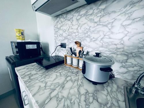 cocina con pared de mármol blanco y fregadero en Saekyung Condotel Near Airport, en Lo-oc