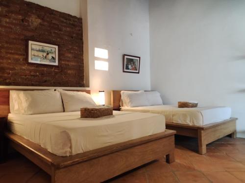 a bedroom with two beds and a brick wall at HOTEL NIETO MOMPOX, ubicado en el corazón del centro histórico, frente al rio magdalena en zona de malecón in Mompos