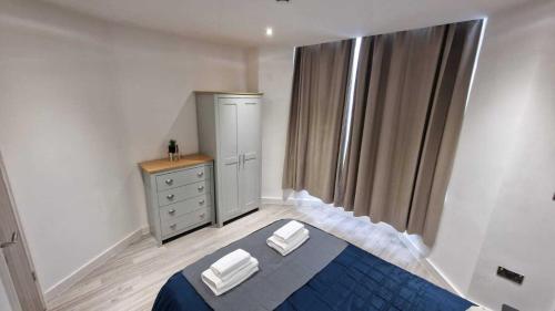 a bedroom with a bed and a dresser and a window at Skyview Strathnairn Apartment 1 in Cardiff