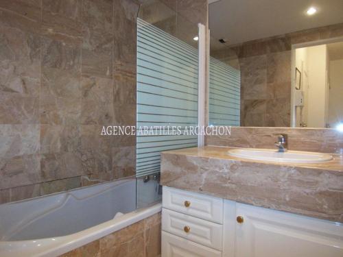 une salle de bain avec un lavabo, une baignoire et un miroir dans l'établissement Jolie T2 à Arcachon - Parking, WiFi, Proche Plage - FR-1-374-3, à Arcachon