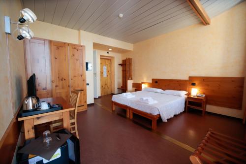 um quarto com uma cama, uma secretária e uma televisão em Pràcatinat Hotel & Restaurant em Fenestrelle