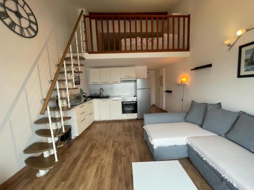 un salon avec un canapé et un escalier en colimaçon dans l'établissement Appartement face à la mer, au Pradet