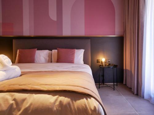 a bedroom with a large bed with pink walls at Eleven by Warren Collection in Sliema