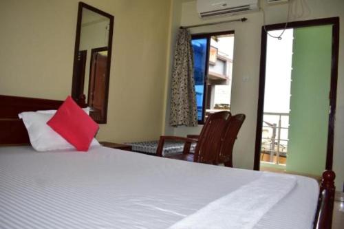 um quarto com uma cama branca e uma almofada vermelha em Hotel Lovely Palace ! Puri em Puri