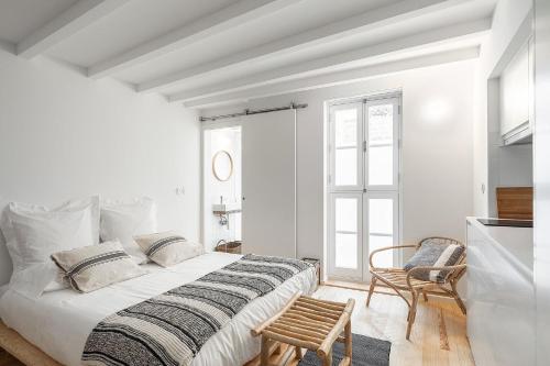 a white bedroom with a large bed and a chair at Loureiro 59 in Coimbra