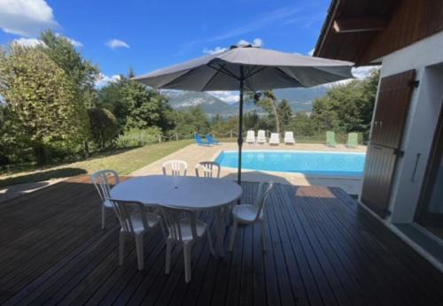 une table et des chaises avec un parasol à côté d'une piscine dans l'établissement Villa avec piscine, vue lac et montagne, à Sévrier