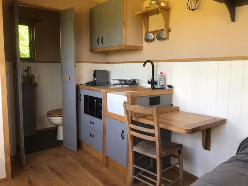a small kitchen with a sink and a wooden table at The Shepherd’s Hut in Whiteparish