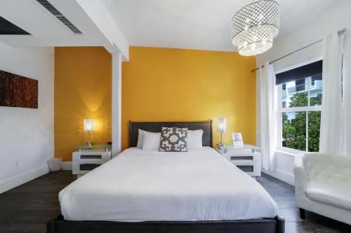 a bedroom with a white bed and a yellow wall at Ithaca of South Beach Hotel in Miami Beach