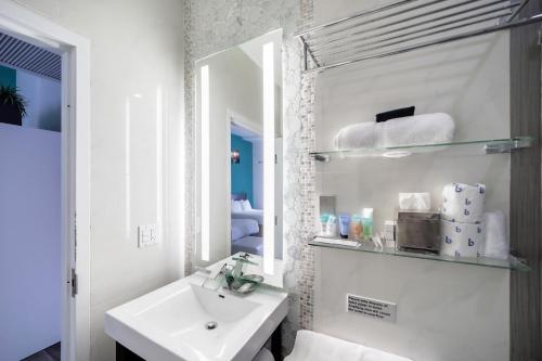 Baño blanco con lavabo y espejo en Ithaca of South Beach Hotel, en Miami Beach