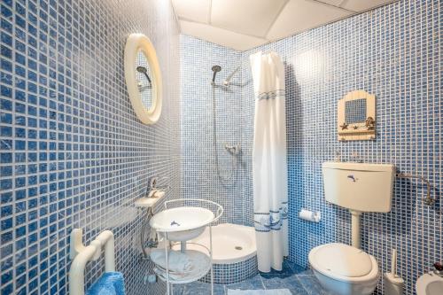 een blauw betegelde badkamer met een toilet en een wastafel bij Eclectic oasis with poolside charm in Arranhó 