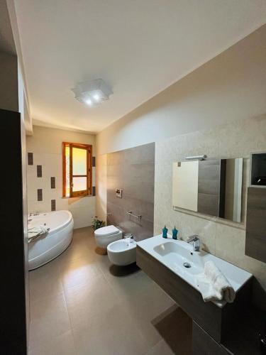 a bathroom with two toilets and a sink and a tub at Casa Manila in Avola