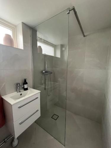 a white bathroom with a shower and a sink at Boende nära centrum och natur in Gothenburg