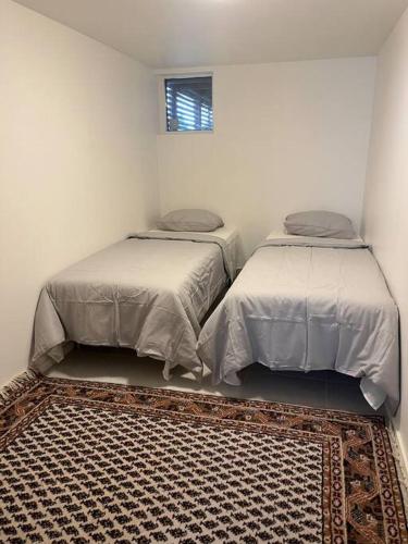 2 bedden in een witte kamer met een tapijt bij Boende nära centrum och natur in Göteborg