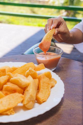 a person is eating a piece of food with chips and sauce at Pousada Sitio Phoenix in Prea