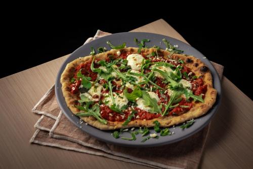 a pizza sitting on a plate on a table at Brut Hotel in Tulsa