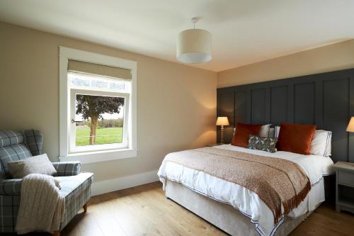Raheen Bridge的住宿－Lovely home close to Killaloe and Lough Derg，一间卧室设有一张床、一个窗口和一把椅子