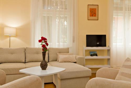 a living room with a couch and a vase with flowers on a table at Kurucz Apartman in Sárospatak