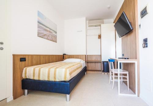 a bedroom with a bed and a tv and a chair at Hotel Angelo in Caorle