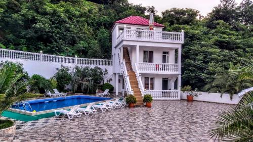 a large white house with a swimming pool and trees at Zura palace in Kvariat'i