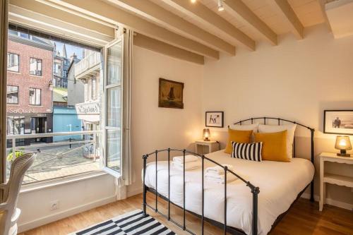 een slaapkamer met een bed en een groot raam bij La Belle Place in Honfleur