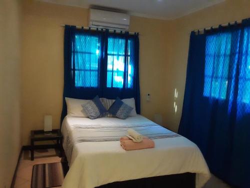 Schlafzimmer mit einem großen Bett und blauen Vorhängen in der Unterkunft Joao's Place in Vila Praia Do Bilene