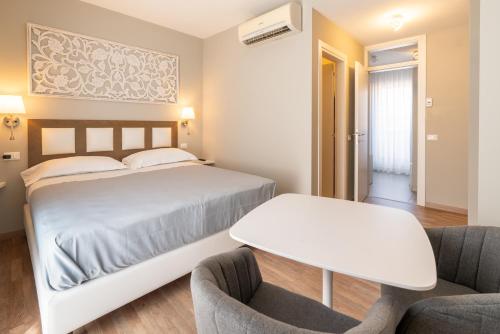 a bedroom with a bed and a table and two chairs at GG8 Hotel & Suite SPA in Gualdo Tadino