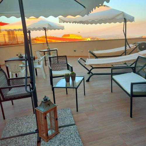 a patio with chairs and tables and an umbrella at Akropoli Exclusive Room in Agrigento