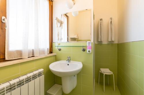 a green bathroom with a sink and a mirror at GG8 Hotel & Suite SPA in Gualdo Tadino
