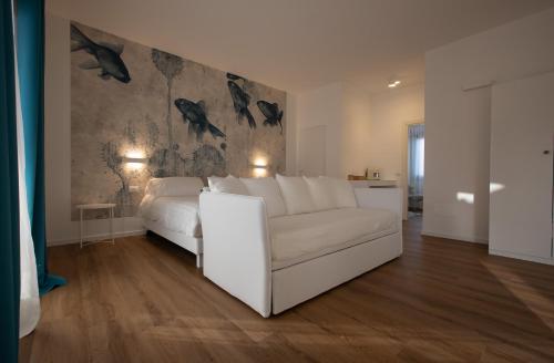 a living room with a white couch and a wall with birds at Il Borgo Boutique Rooms by KasaVacanze in Porto San Paolo