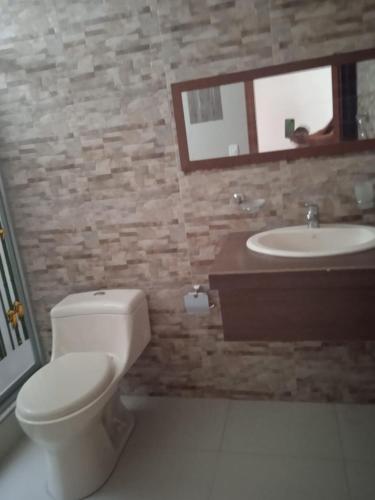 a bathroom with a toilet and a sink and a mirror at Departamento grande 4 dormitorios, 3 baños con garage gratuito in Quito
