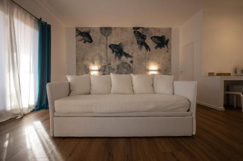 a white couch in a living room with a painting at Il Borgo Boutique Rooms by KasaVacanze in Porto San Paolo