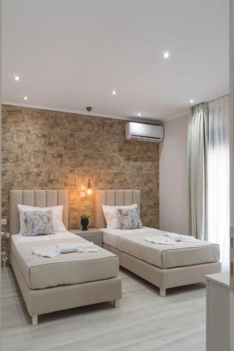 a bedroom with two beds and a brick wall at LUXURY VILLAS ELENI STEFI in Limenas